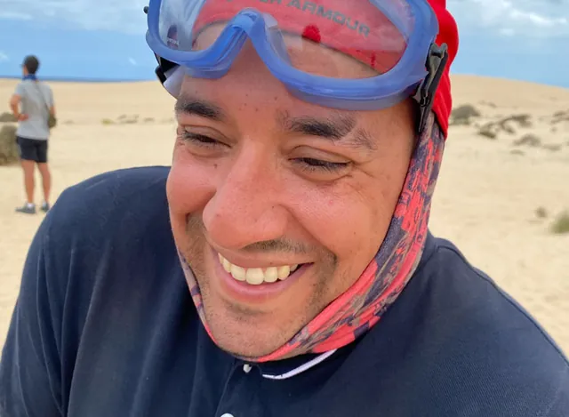 Sourire d'un membre de l'équipe dans les dunes, lunettes de protection sur le front
