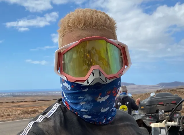 Un membre de l'équipe en lunettes et foulard, prêt pour la sortie en buggy