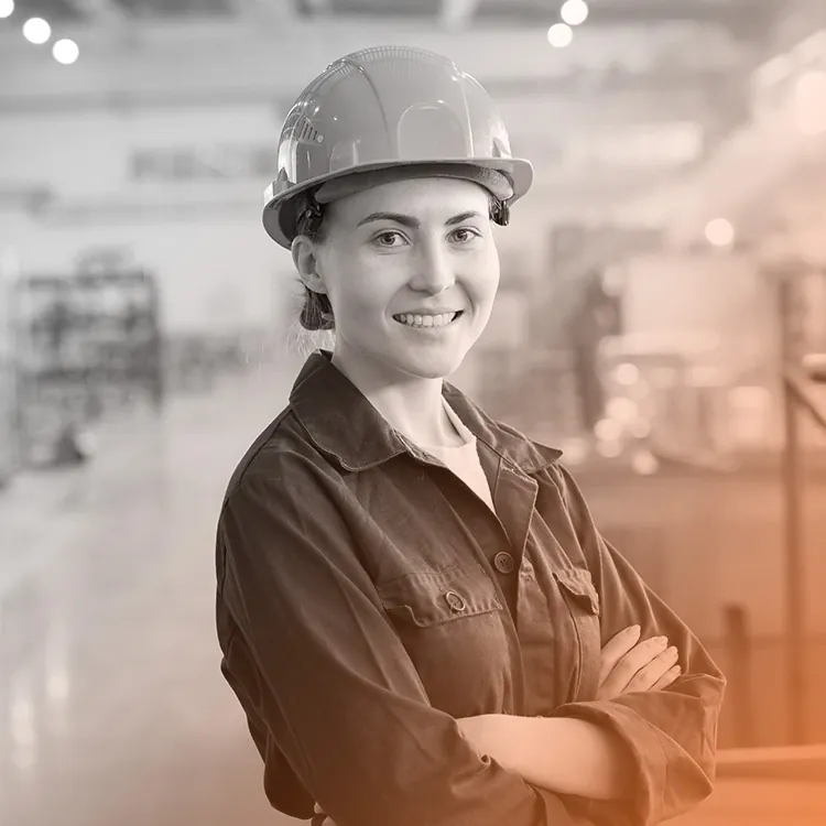 Technicienne casquée, bras croisés, dans un atelier industriel