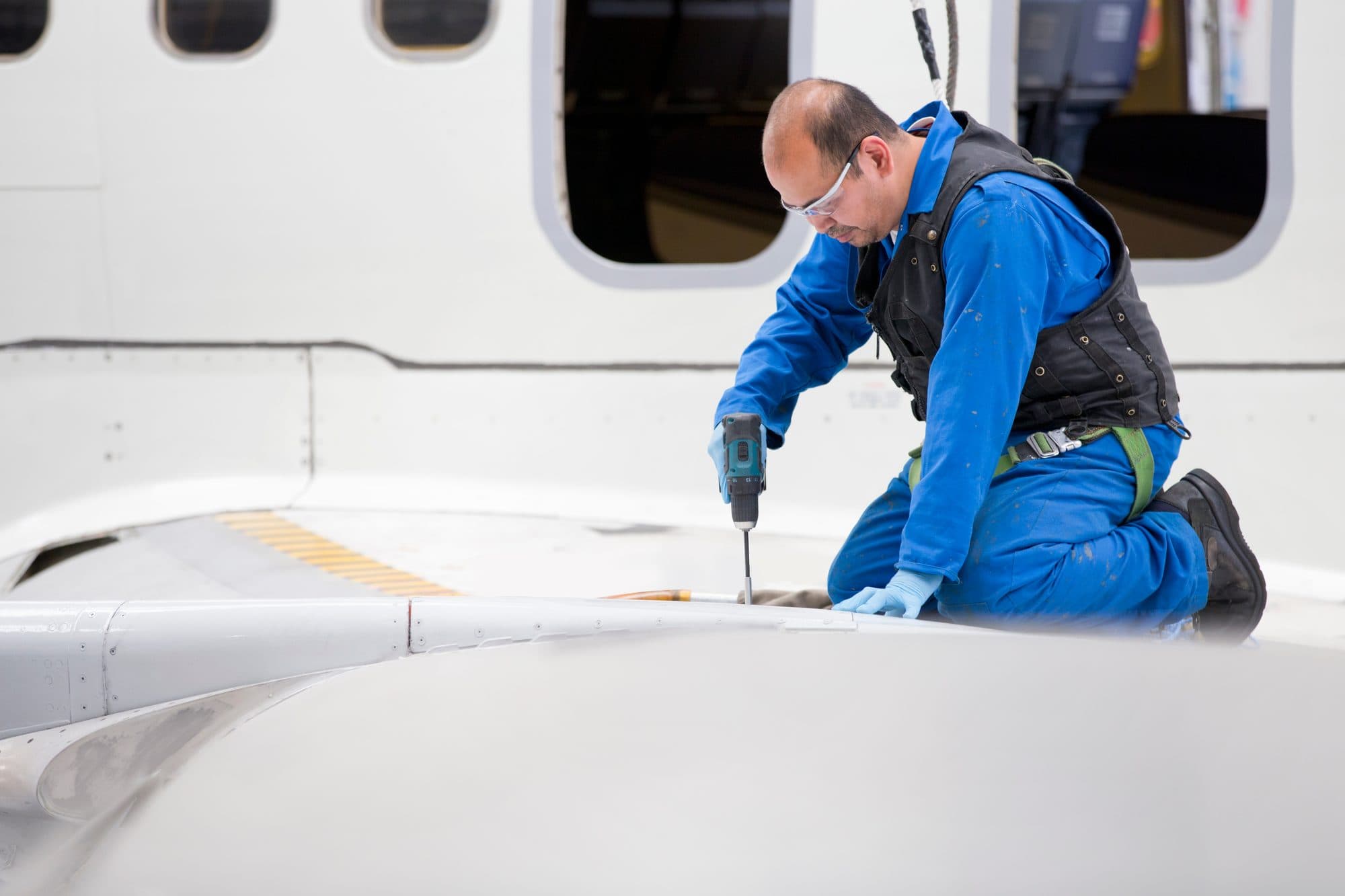 Technicien perçant l'aile d'un avion de ligne en hangar
