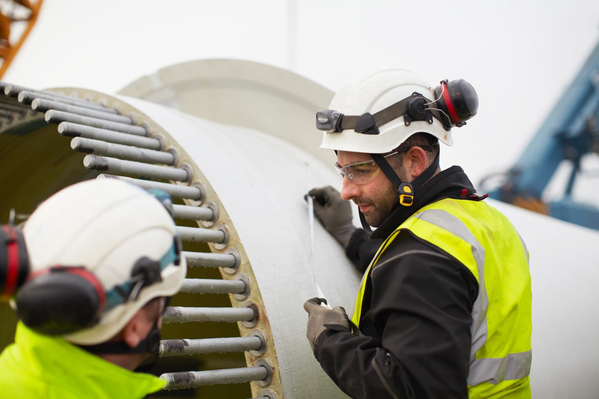 Deux techniciens sur la bride boulonnée d'un mât d'éolienne