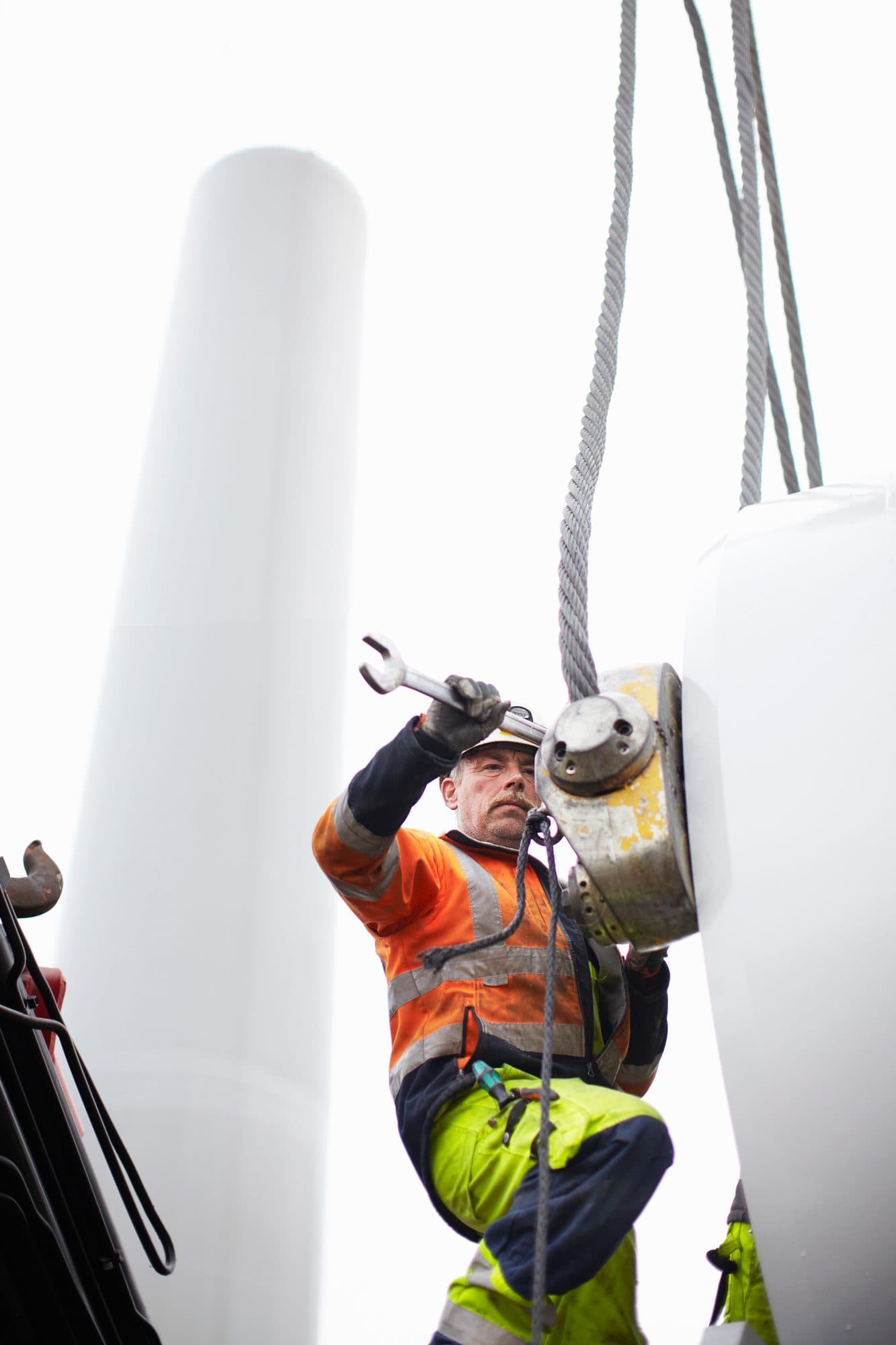 Technicien senior sous les élingues d'un levage d'éolienne