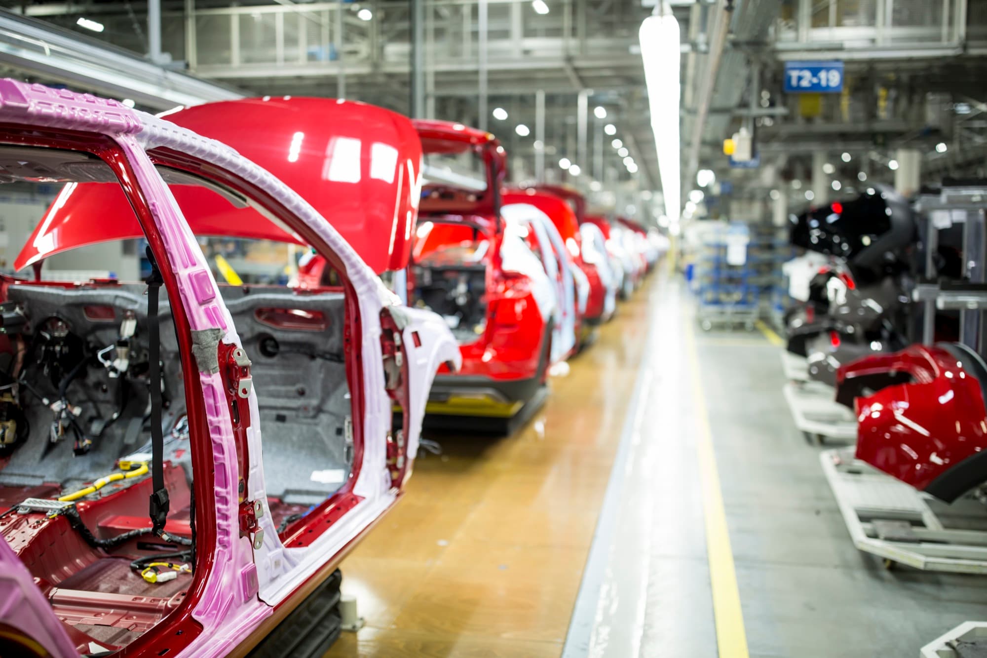 File de caisses de voitures rouges en cours d'habillage sur la ligne d'assemblage d'une usine automobile