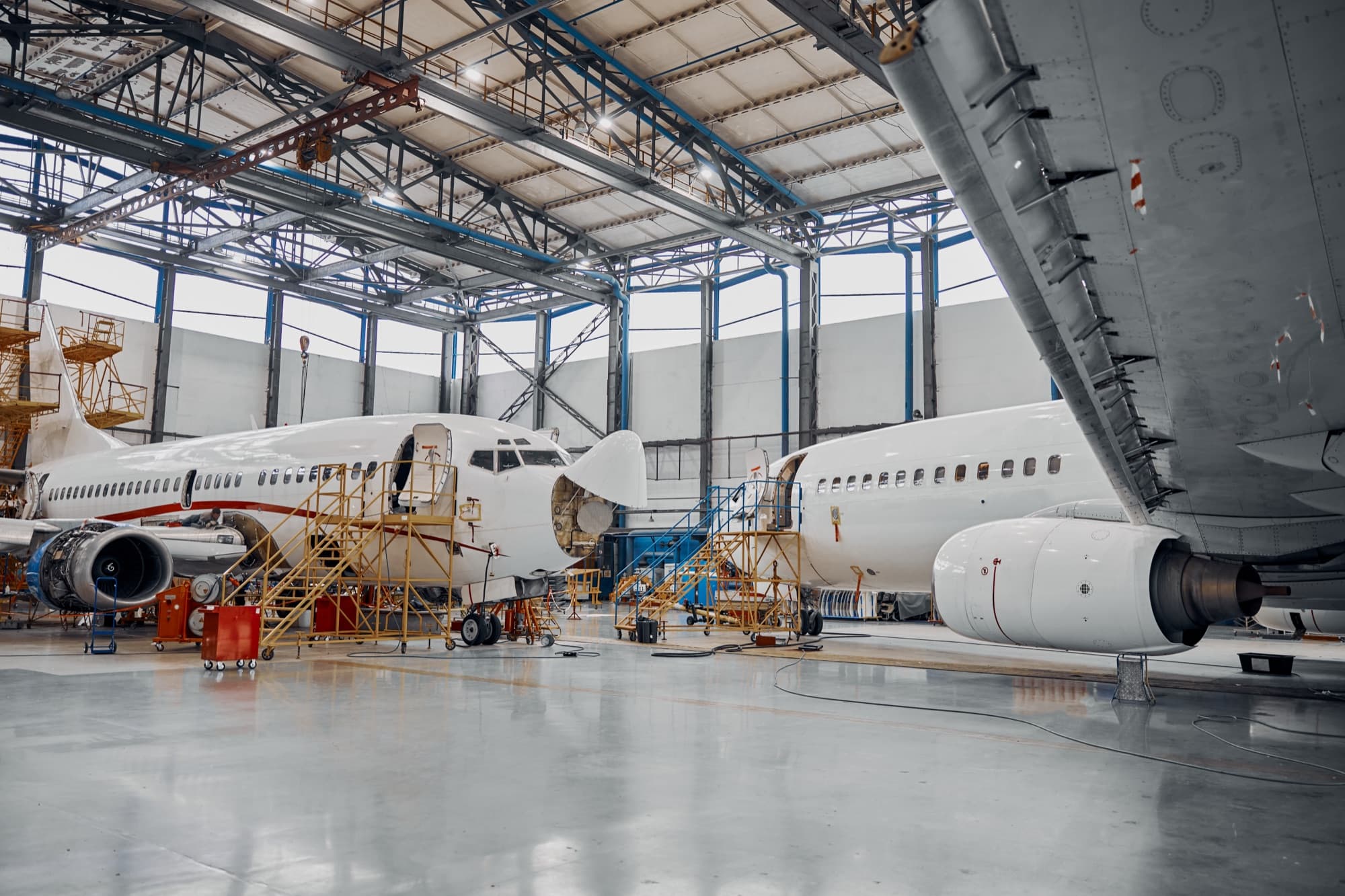 Deux avions de ligne ouverts et entourés d'échafaudages dans un hangar de maintenance
