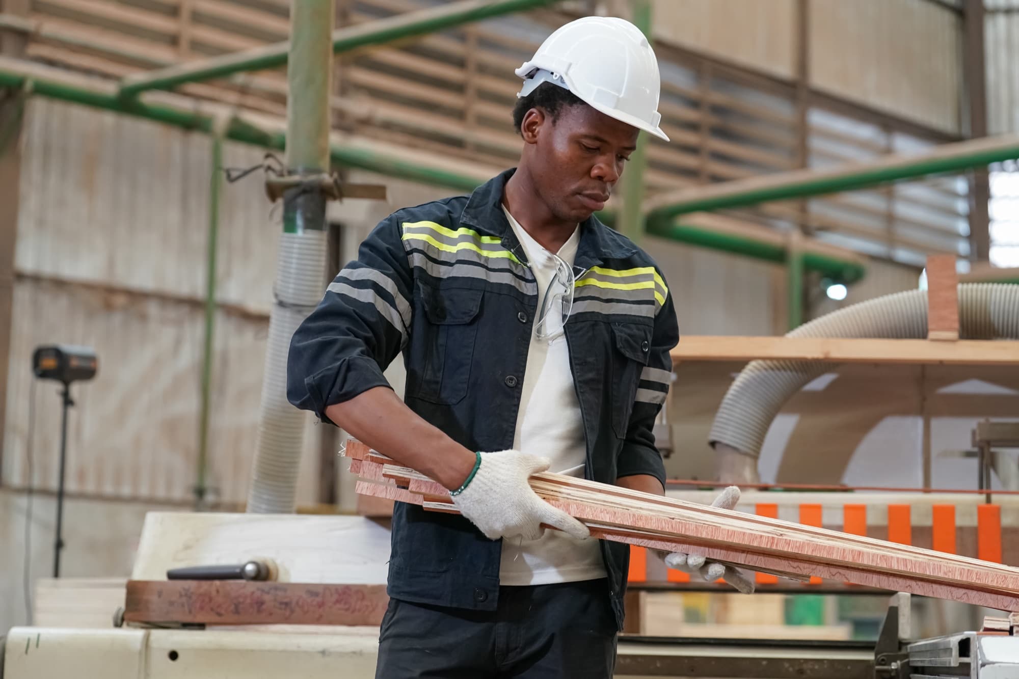 Opérateur casqué engageant un paquet de lattes de bois sur la table d'une machine de seconde transformation
