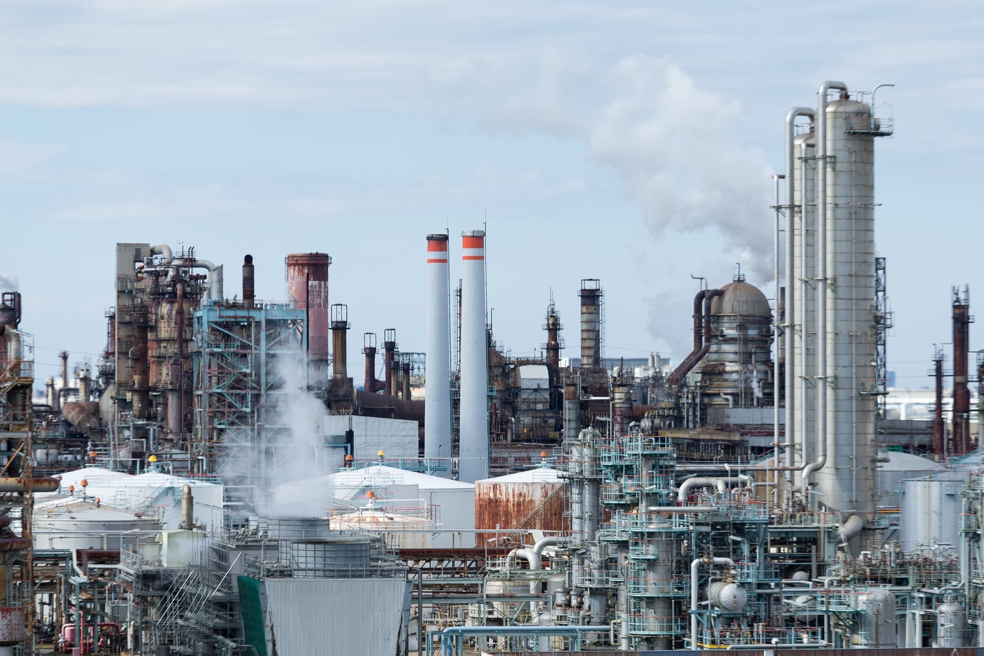 Vue d'ensemble d'un complexe pétrochimique hérissé de colonnes de distillation et de cheminées fumantes