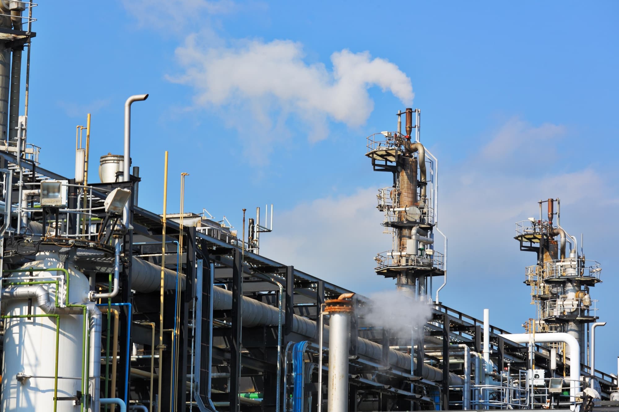 Colonnes de distillation et racks de tuyauterie d'une unité pétrochimique sous un ciel bleu