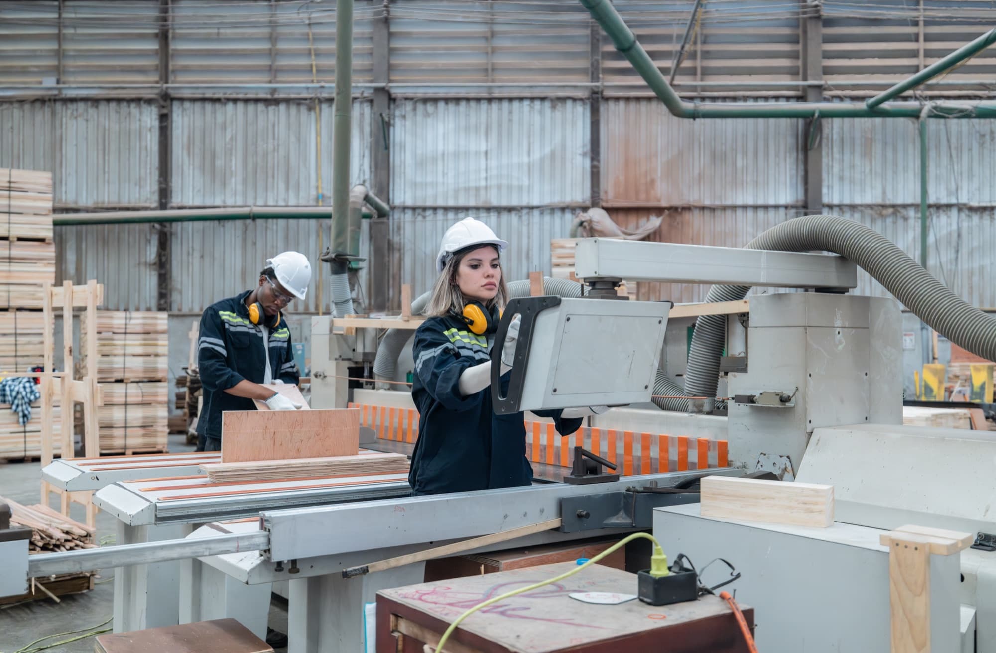 Deux opératrices conduisant une machine à bois avec aspiration dans un atelier de seconde transformation