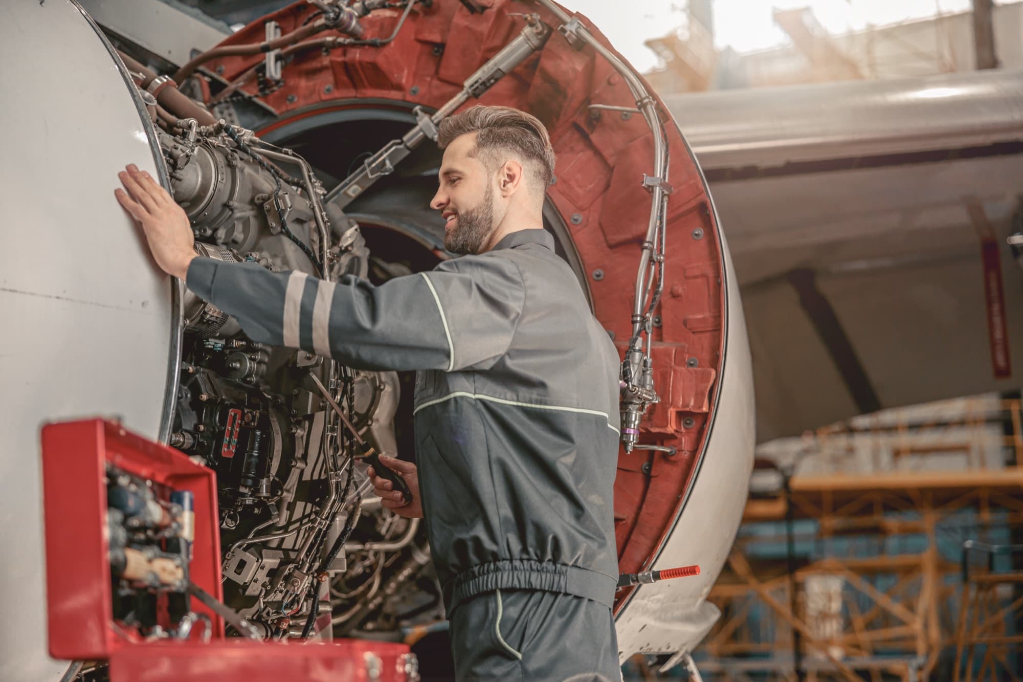 Mécanicien aéronautique intervenant sur un réacteur capot ouvert dans un hangar de maintenance