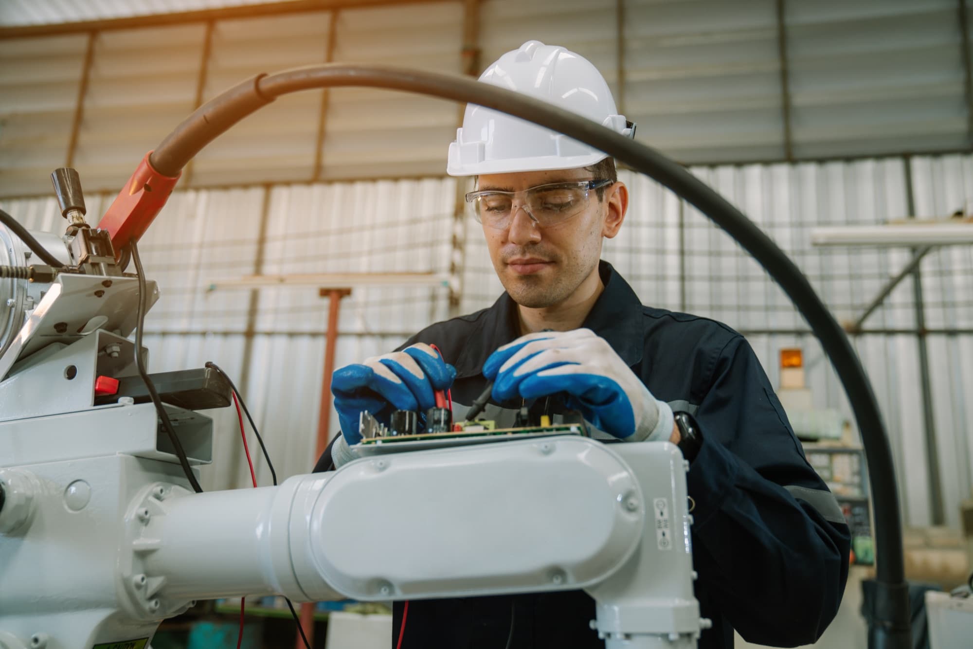 Technicien en casque blanc ajustant la carte électronique montée sur le bras d'un robot blanc