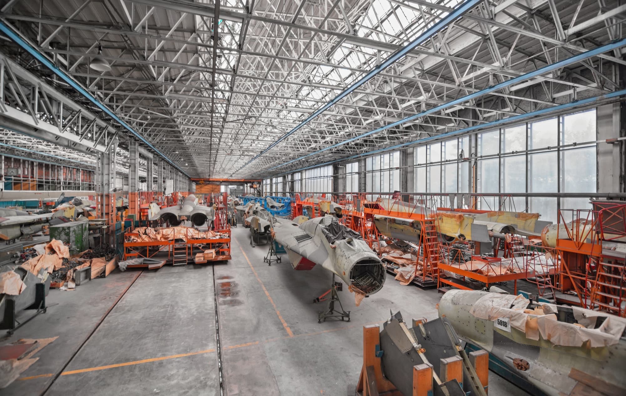 Halle d'assemblage aéronautique alignant des fuselages en cours de montage sous une verrière