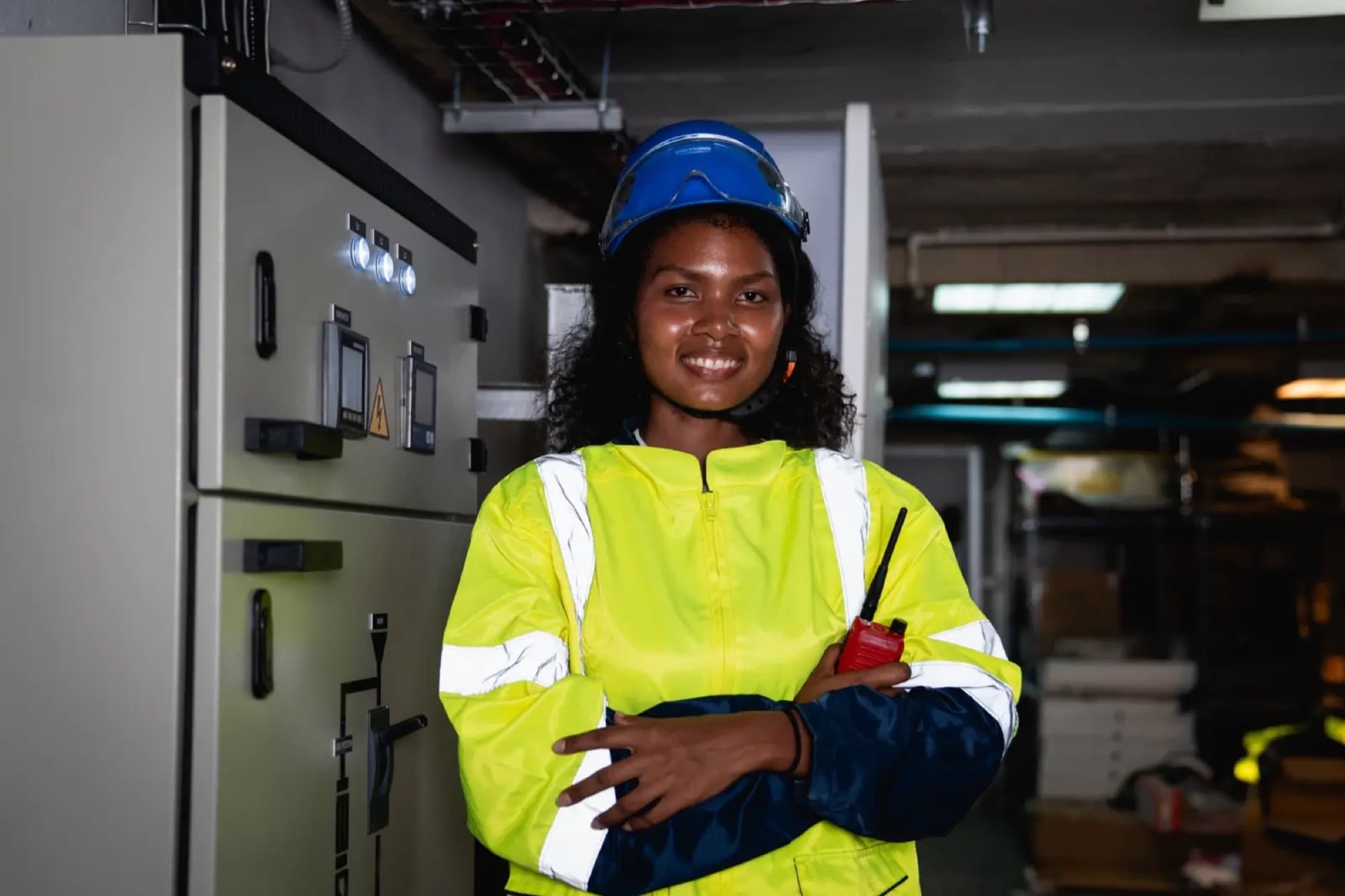 Technicienne avec radio portative devant une cellule d'armoire électrique de distribution