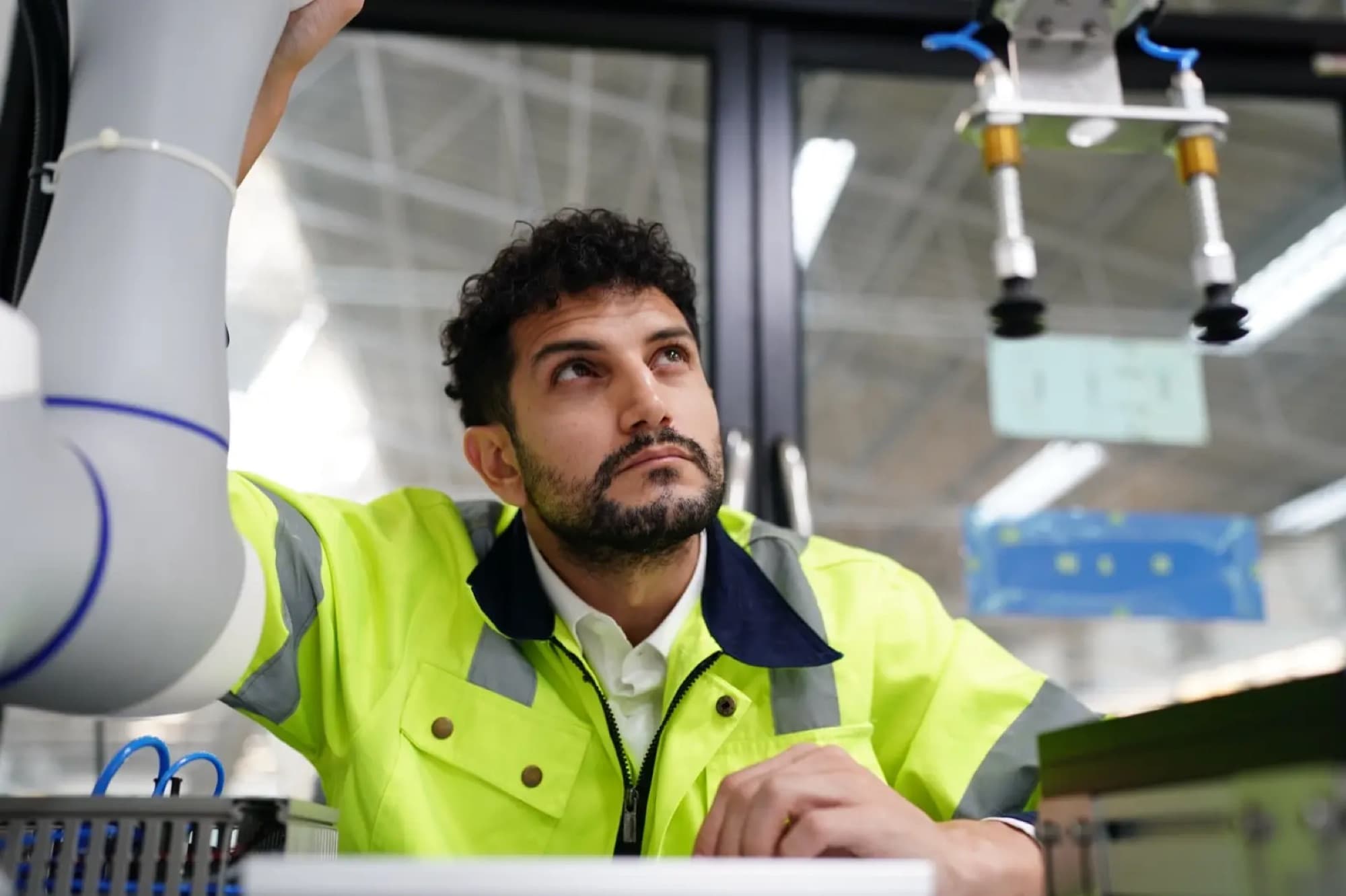 Technicien observant une préhension à ventouses montée sur un bras collaboratif, flexibles pneumatiques apparents