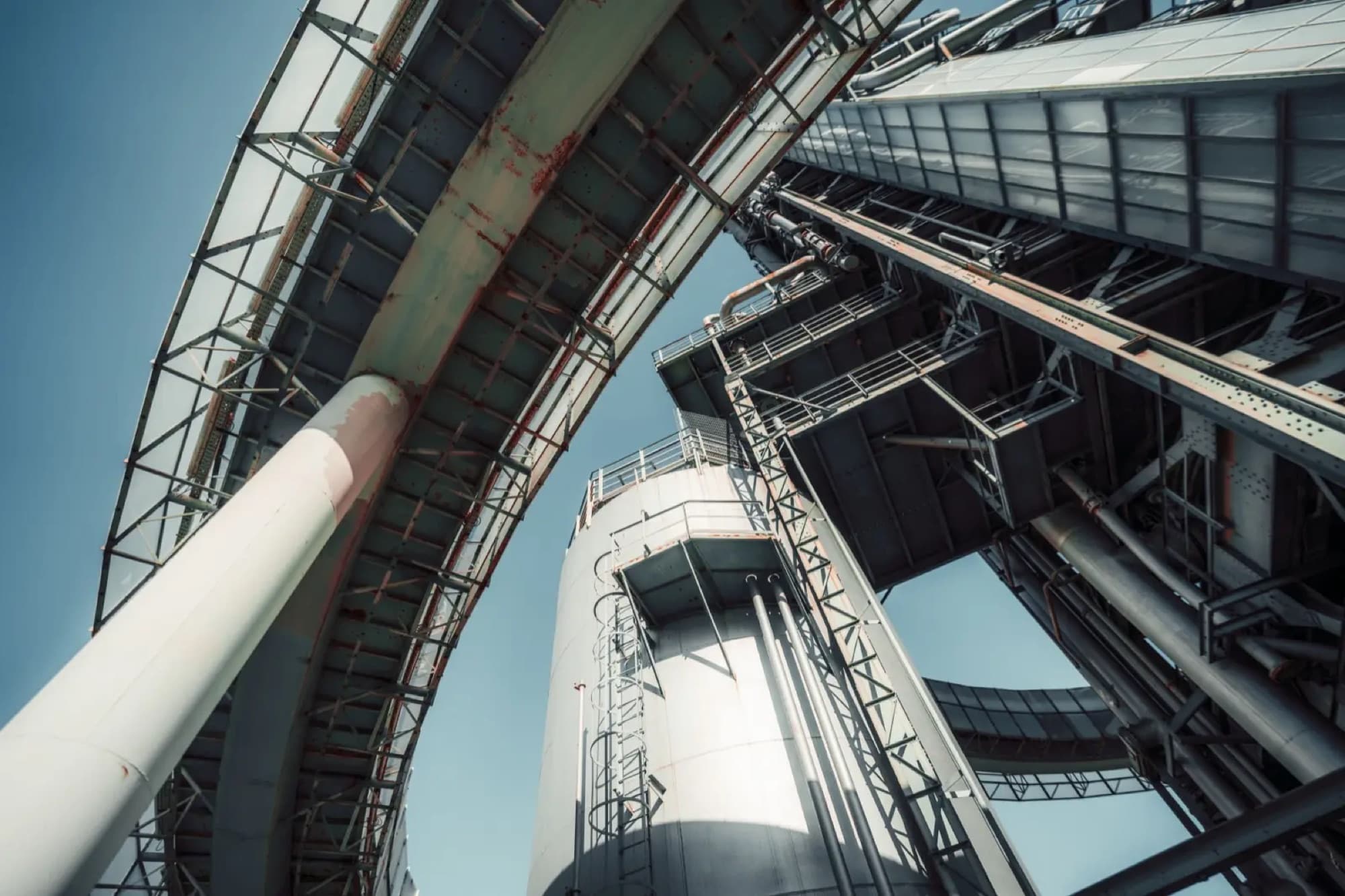 Contre-plongée sur un silo, des convoyeurs capotés et de grosses conduites d'une installation de vrac