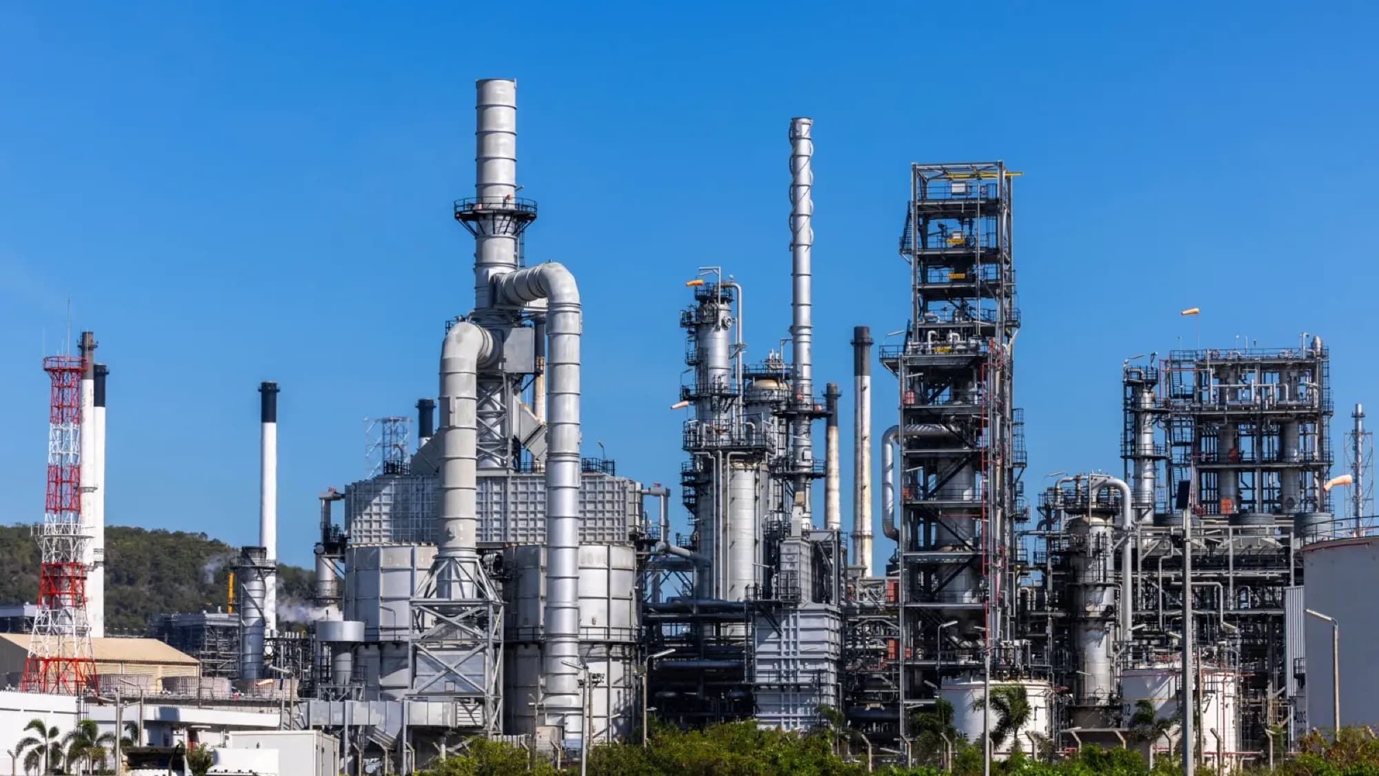 Raffinerie pétrochimique vue de l'extérieur en plein jour, colonnes de distillation, cheminées et réseaux de tuyauterie