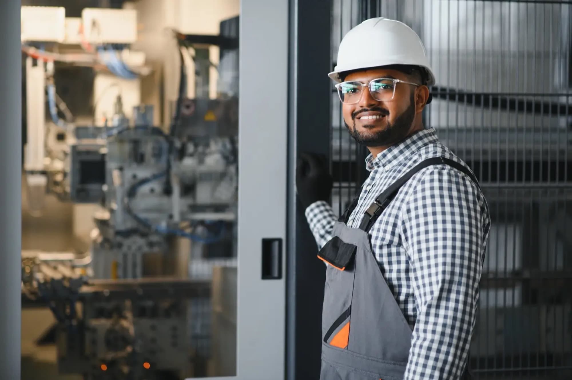 Technicien à la porte vitrée d'une machine automatisée équipée de vérins et de flexibles