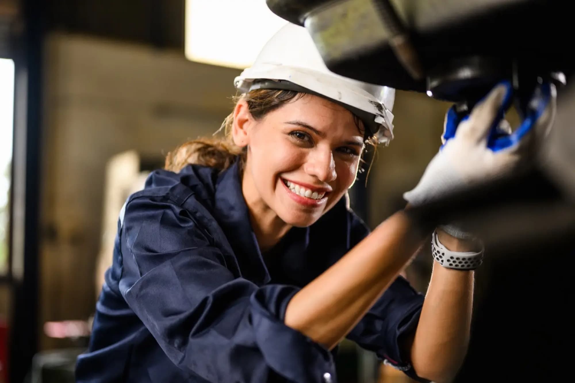Technicienne gantée intervenant sur un organe de machine en atelier, vue rapprochée