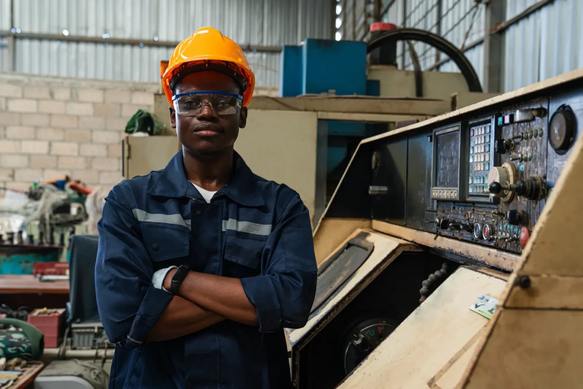Technicien bras croisés devant le pupitre de commande numérique d'une machine-outil dans un atelier