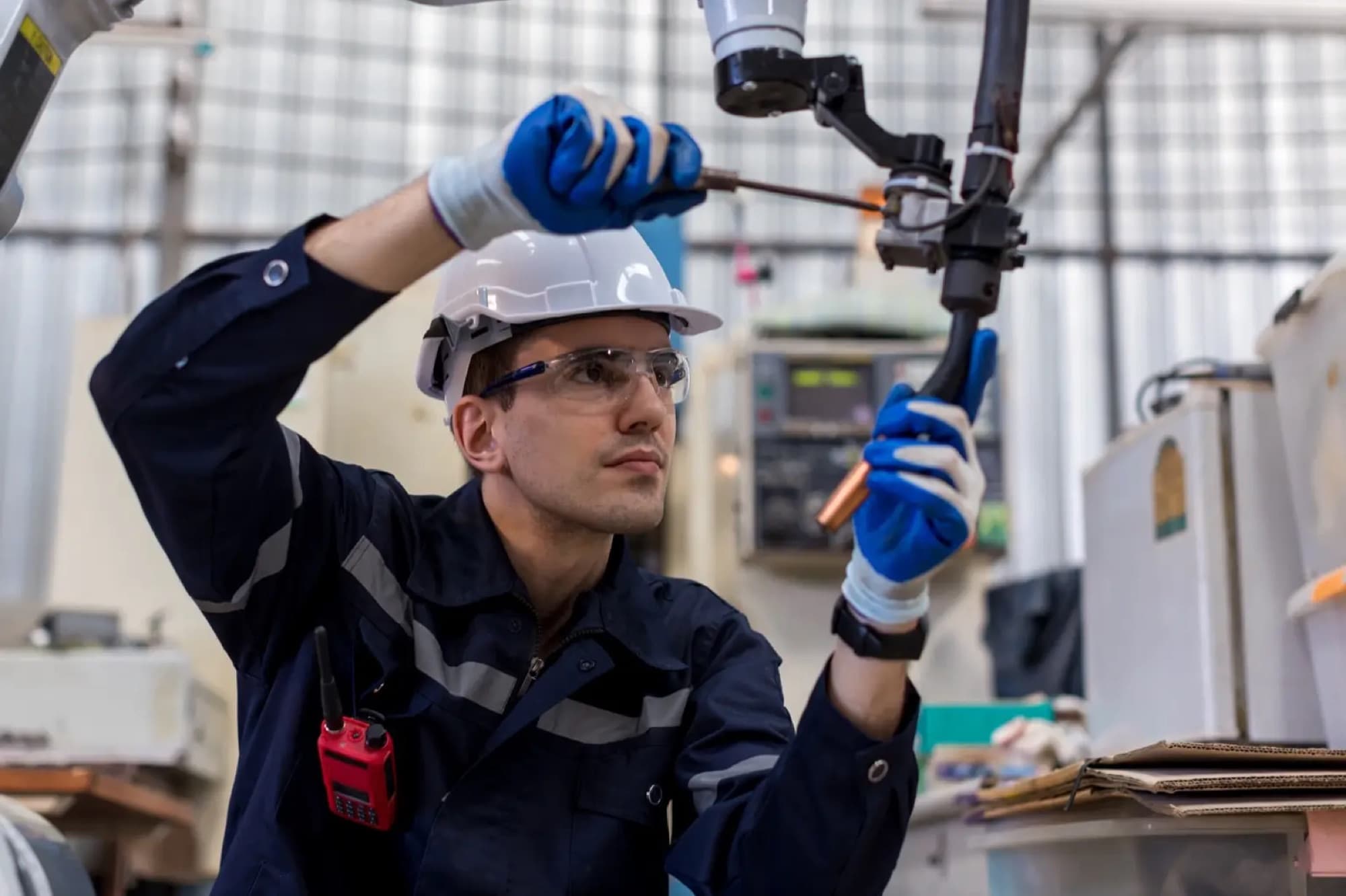 Technicien remplaçant le tube contact de la torche de soudage d'un robot en atelier