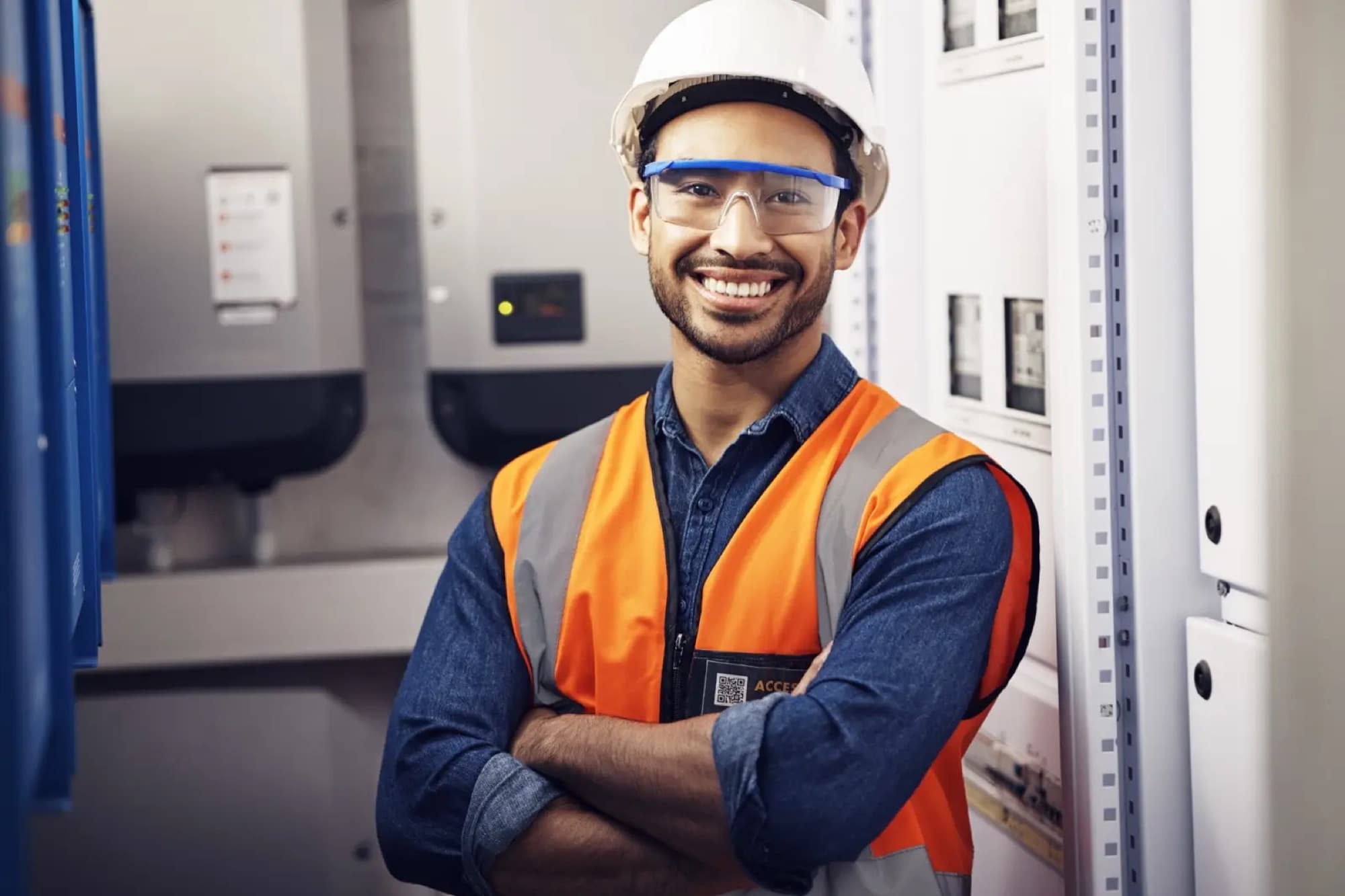 Technicien bras croisés devant une armoire électrique de distribution en local technique
