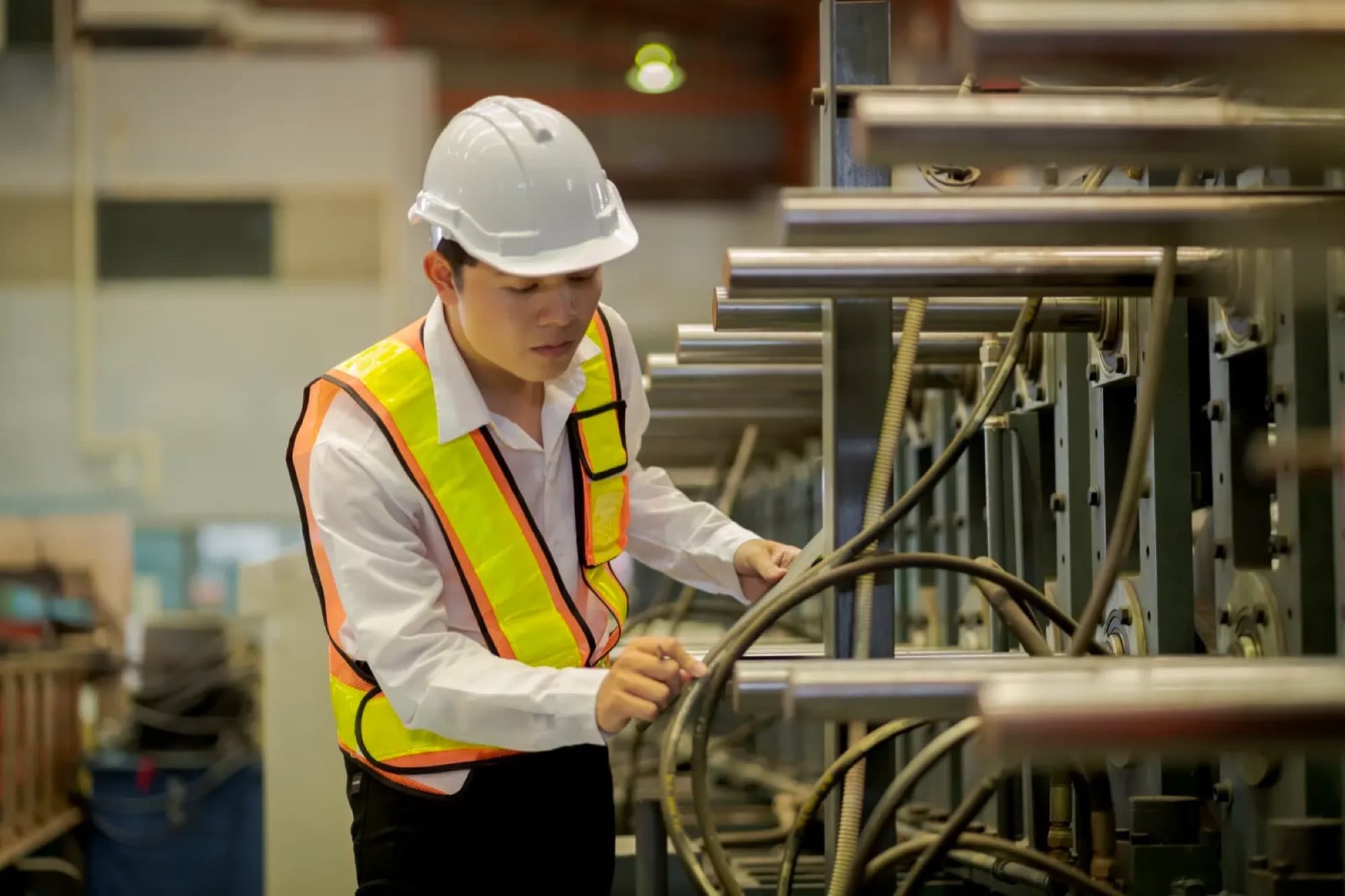 Technicien inspectant les vérins chromés et les flexibles d'une presse hydraulique en atelier