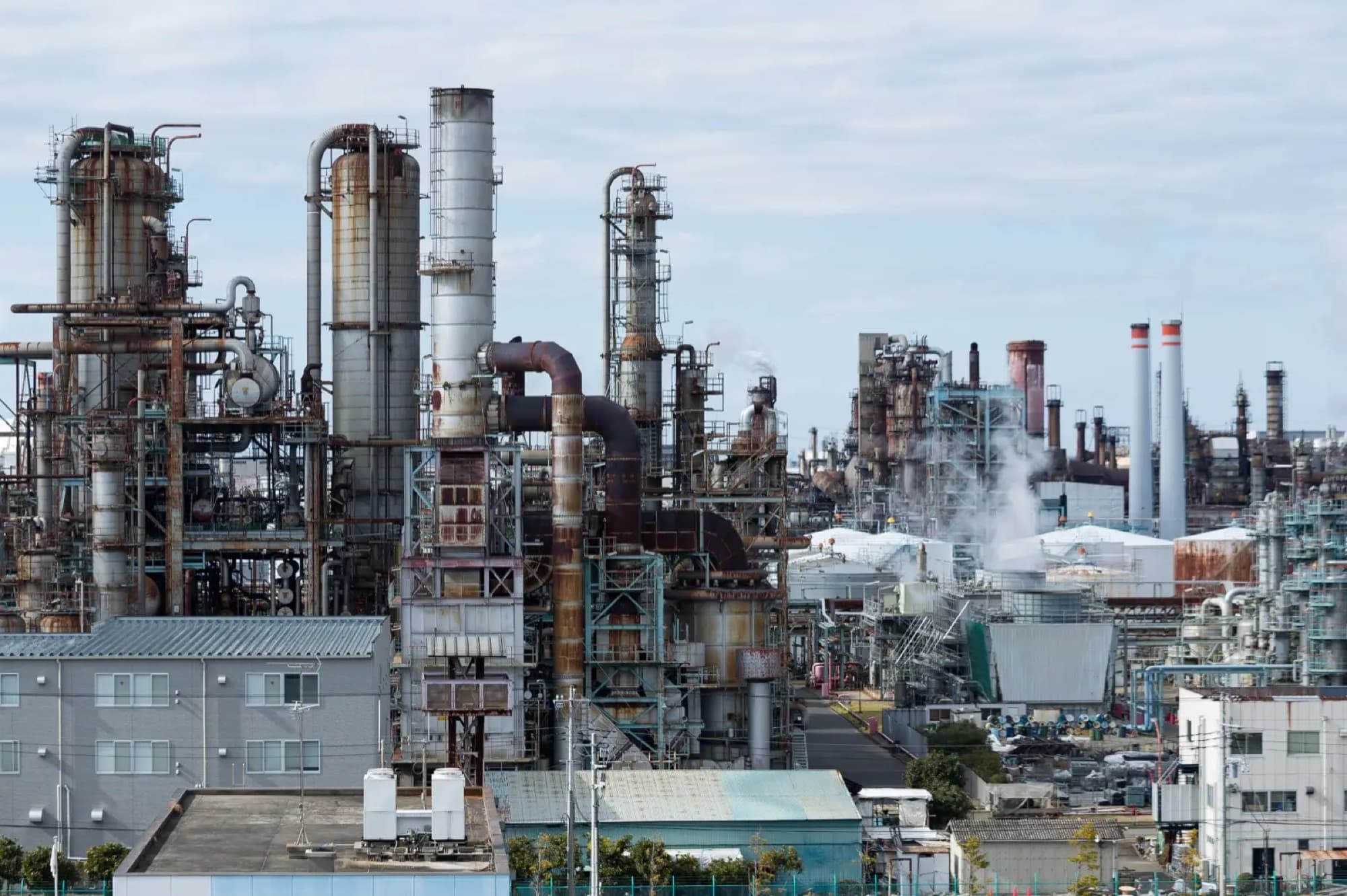 Raffinerie pétrochimique vue depuis les toits voisins, colonnes de distillation, tuyauteries et cheminées