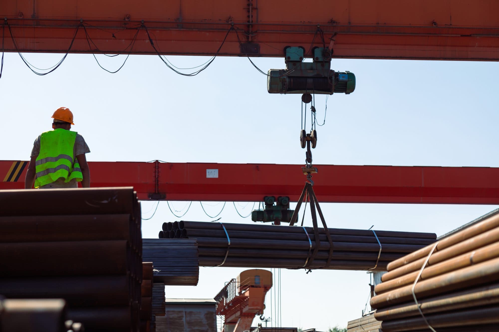 Portique de levage déplaçant un fagot de tubes en parc extérieur