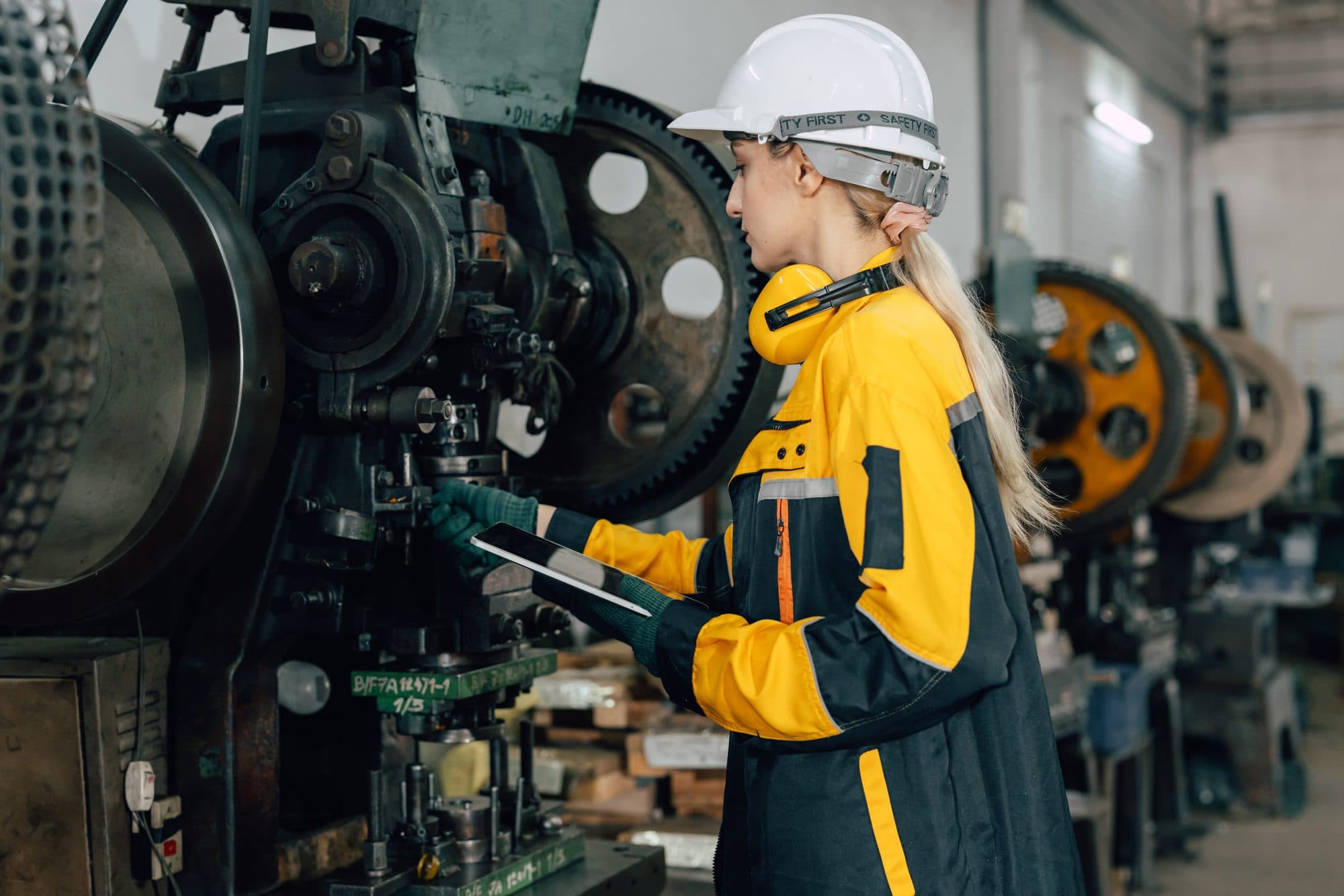 Technicienne auditant une rangée de presses mécaniques à volant