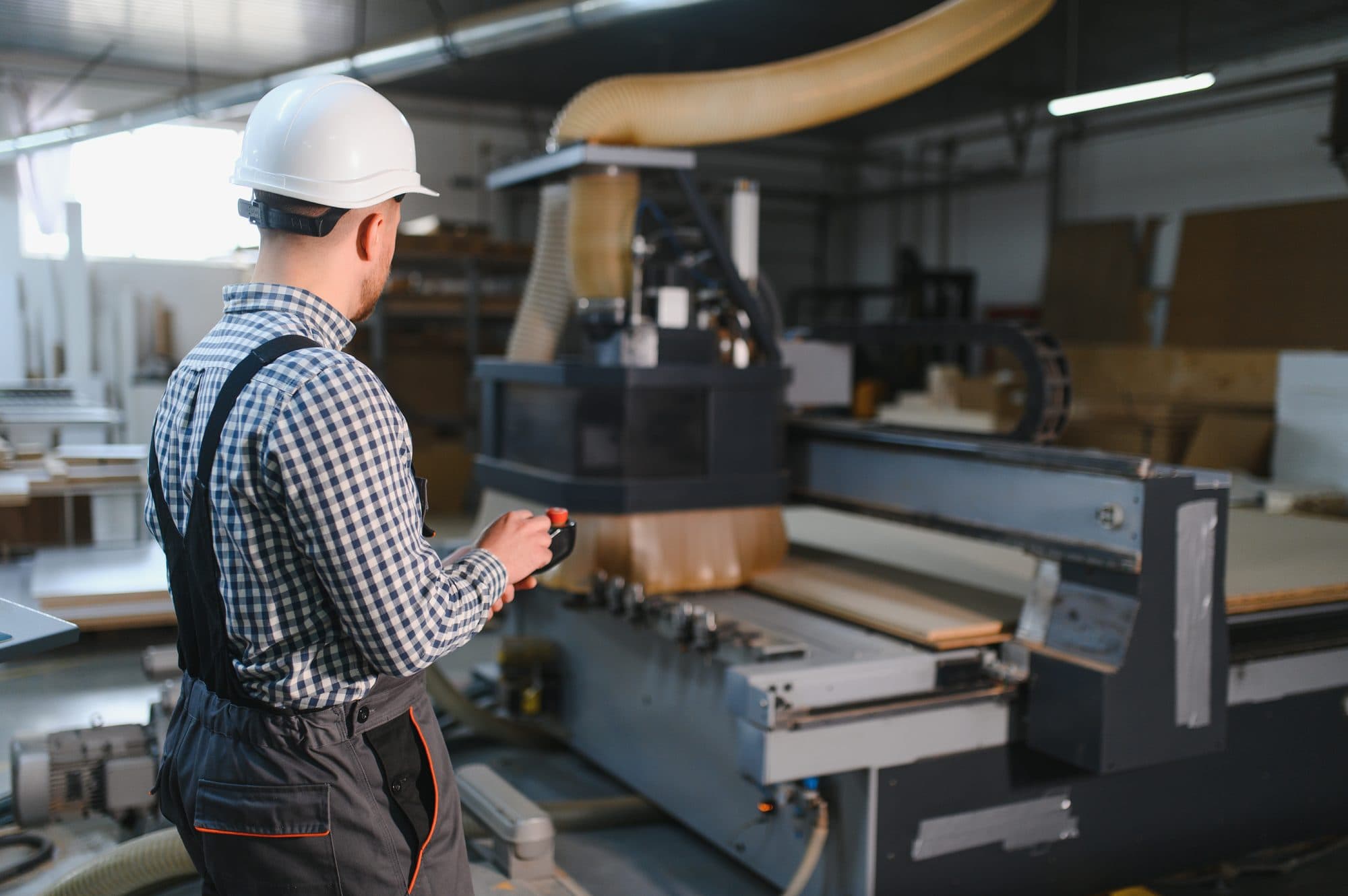 Technicien casqué pilotant une CNC à panneaux