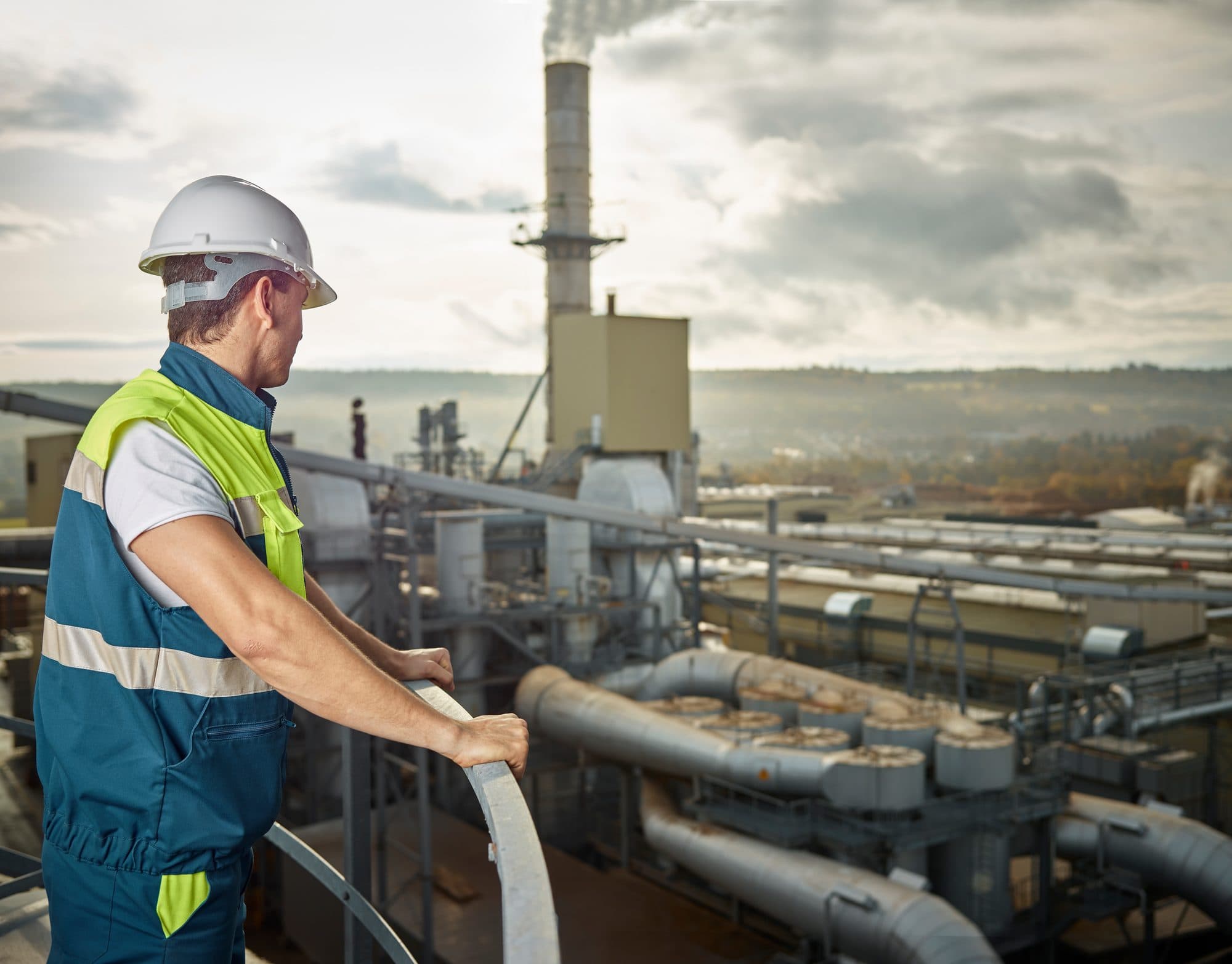 Technicien sur une passerelle dominant une usine du bois