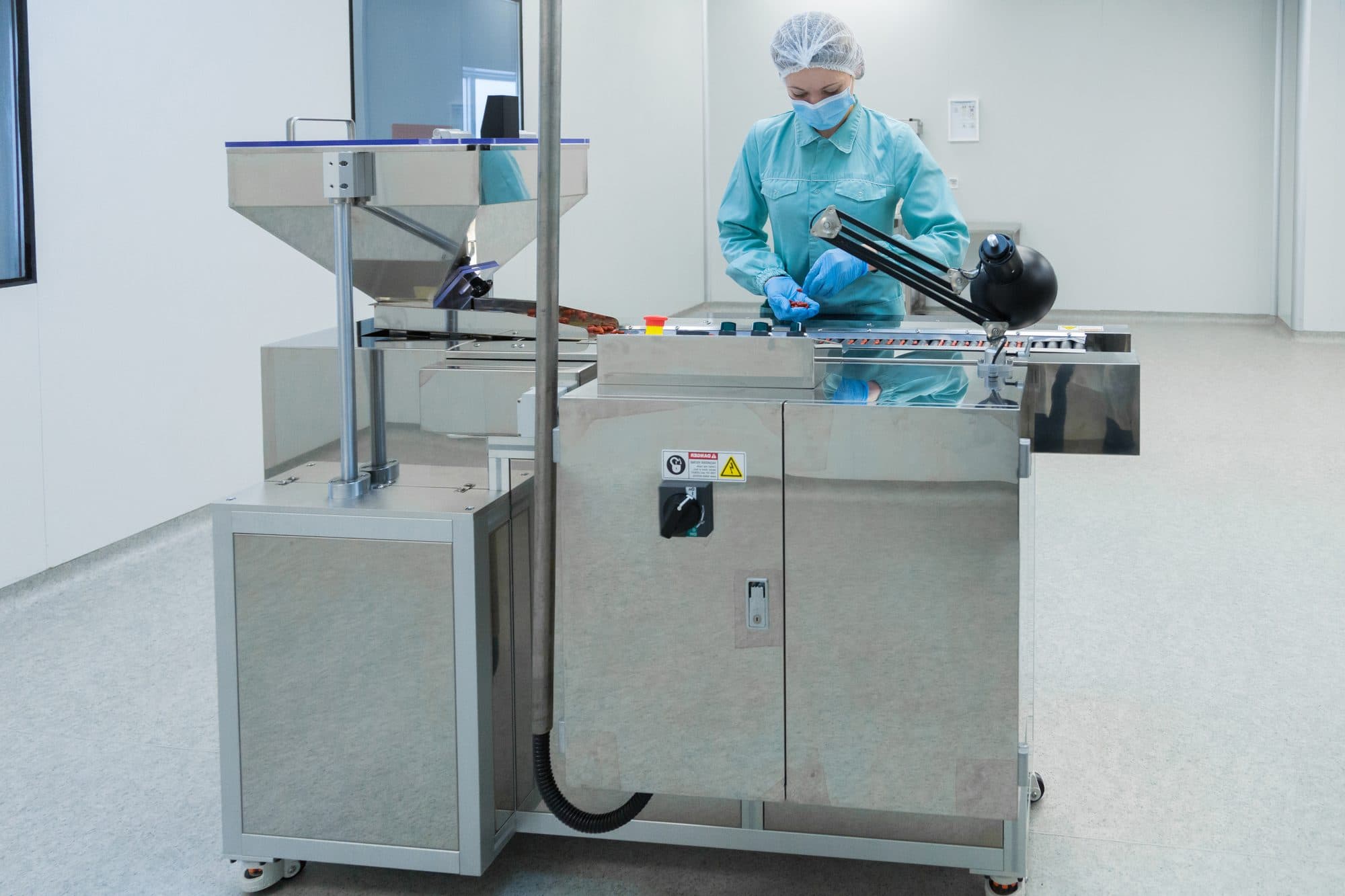 Technicienne en zone stérile réglant une machine à comprimés