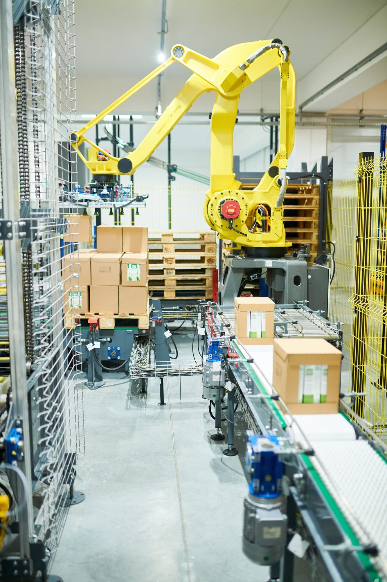Robot palettiseur en fin de ligne derrière clôture