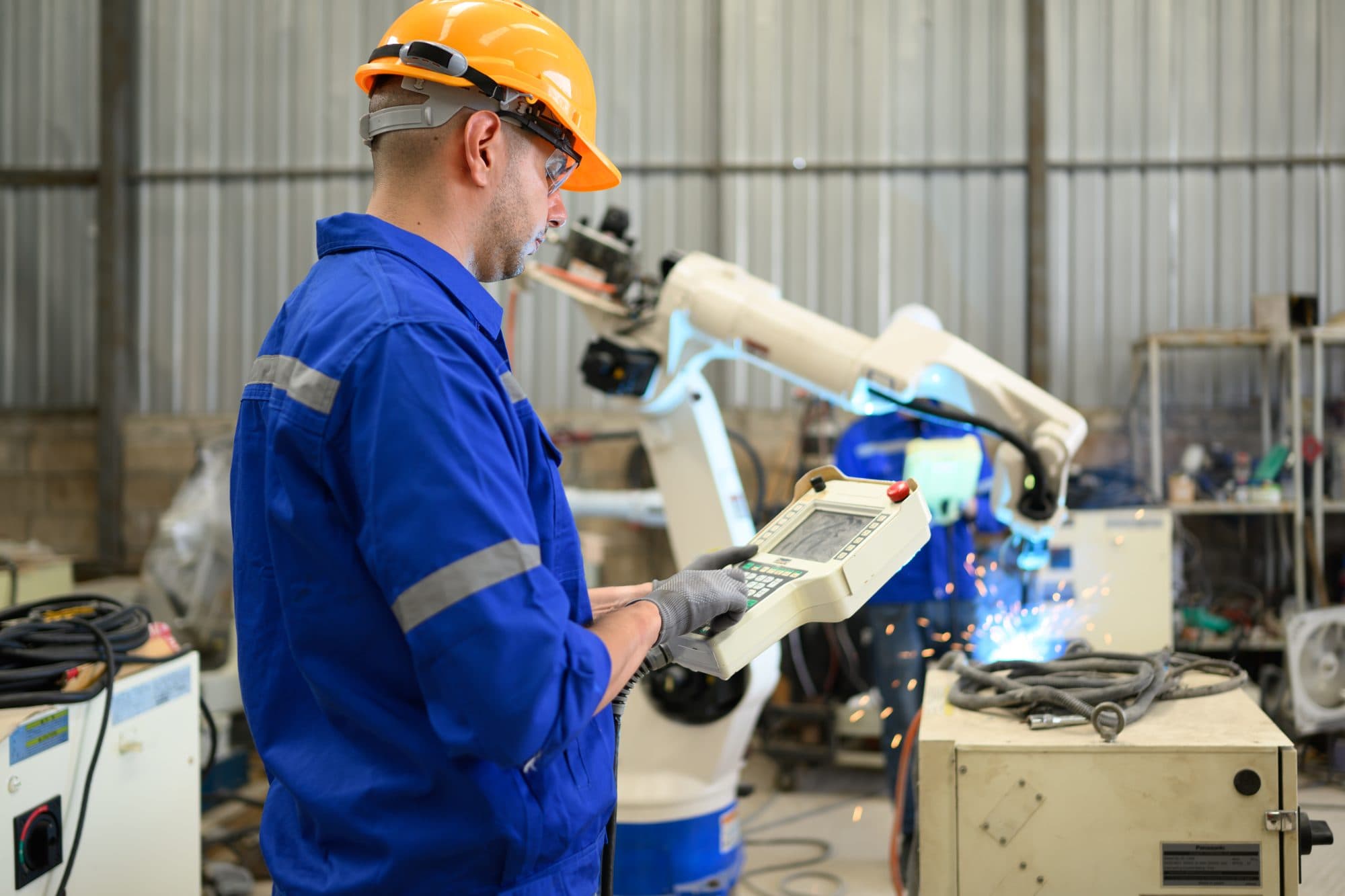 Technicien senior au pupitre d'apprentissage d'un robot de soudure