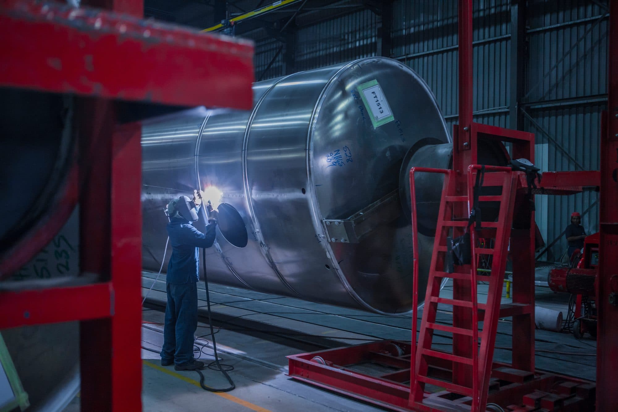 Soudeur sur une grande virole inox en atelier de chaudronnerie