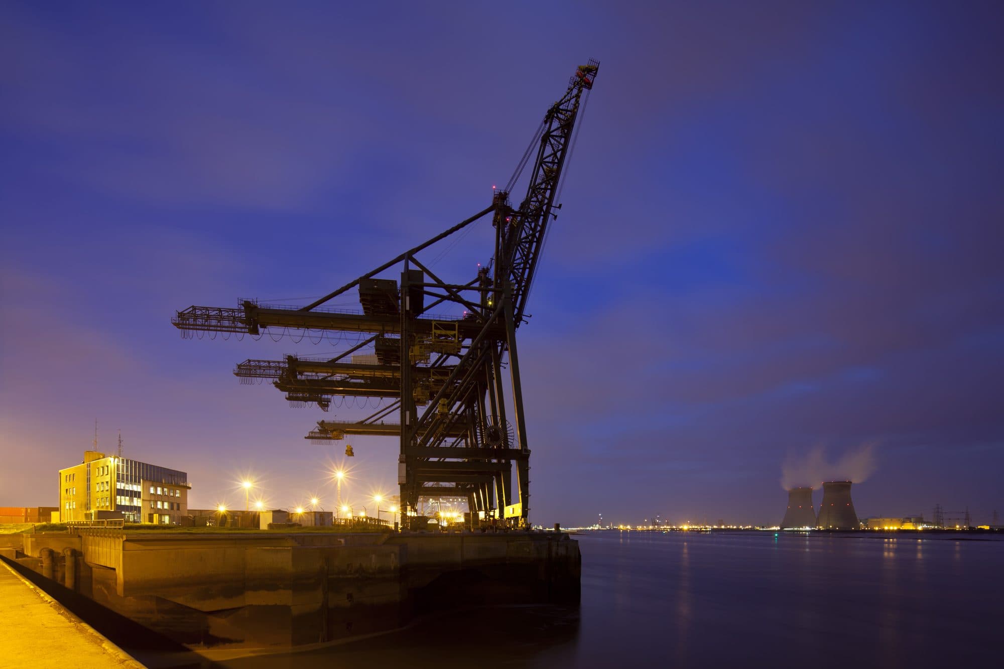 Portique portuaire de nuit, centrale électrique au loin